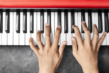 Closeup view of human hand playing electronic piano keyboard with black background