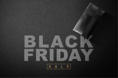 Gift box with black ribbon and Black Friday sale text on a black background. Black Friday concept