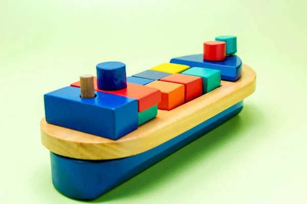 A colorful wooden toy ship on a colored background