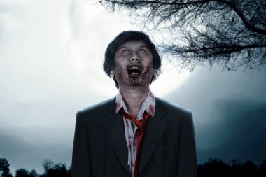 Scary zombie with blood and wound on his body standing with full moon background