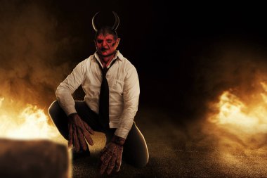 Devilman is sitting with the fire's background. Halloween concept