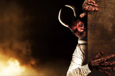 Devilman is standing behind the wall with the fire's background. Halloween concept