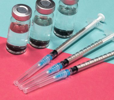 Medical Equipment that includes Syringes with Hypodermic Needles with Safety Caps and vials Containing a clear Liquid.