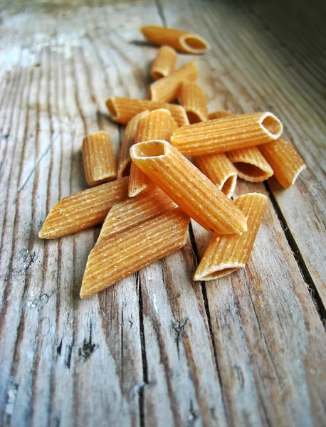 Uncooked brown pasta selection on a wooden rustic background — Stock Photo, Image