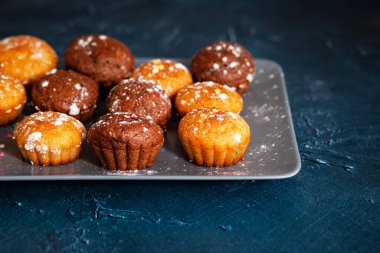 Lezzetli çikolatalı ve vanilyalı kekler. Beton desenli masa, üst manzara. Pudra şekerli tatlı hamur işleri 