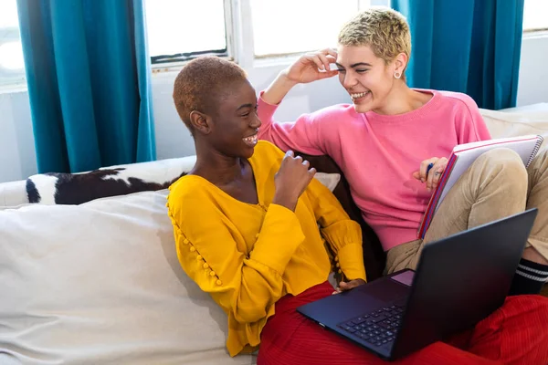 Uśmiechnięte kobiety korzystające z laptopa siedząc na kanapie w domu — Zdjęcie stockowe