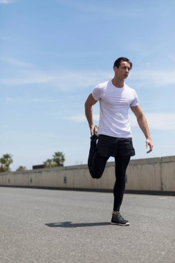 Sportif adam bacaklarını açık havada açıyor..