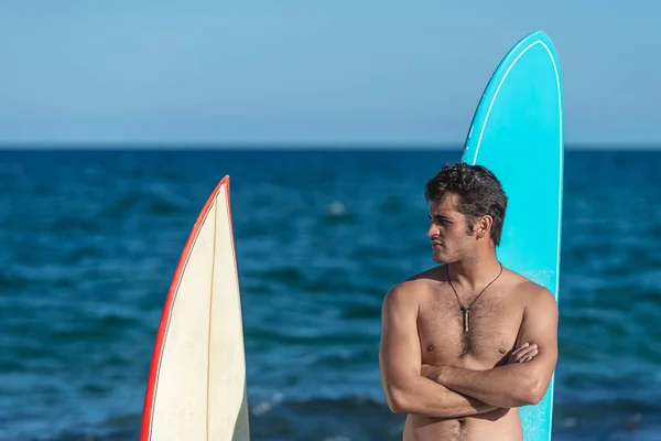 穿着蓝色短裤的性感的非常英俊的晒黑了的年轻人的特写画像 并在海滩上配备了一个冲浪板 冲浪模型 — 图库照片