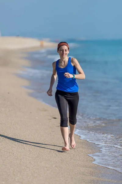 Genç bir kadın sabahları kumsalda koşar.