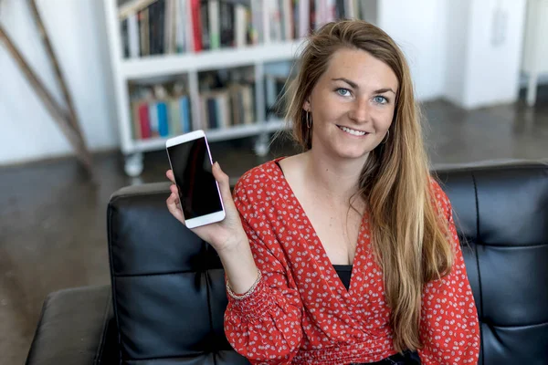 Young Woman Sitting Sofa Holding Mobile Phone While Looking Toothly — Foto de Stock