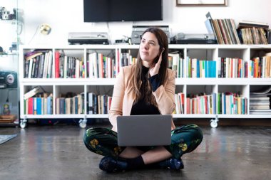 Genç ve güzel girişimci kadın evde otururken dizüstü bilgisayar kullanıyor..