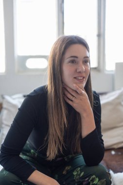 Kafasından vurulan çekici beyaz kadın kanepede oturuyor oturma odasında kanepe, gülümseyen genç kadın, kameraya bak.