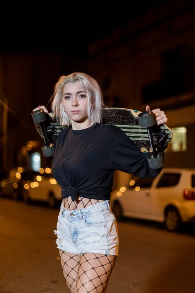 도시에서 스케이트 보드를 거리에 서있는 반바지에 카메라를 여자의 전면보기 — 스톡 사진