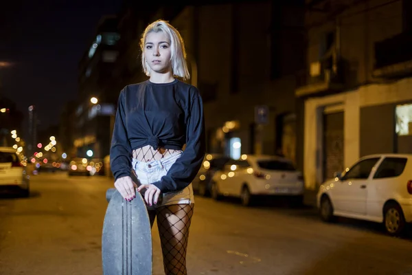 여자가 스케이트보드를 거리에 반바지를 바라보고 있습니다 — 스톡 사진