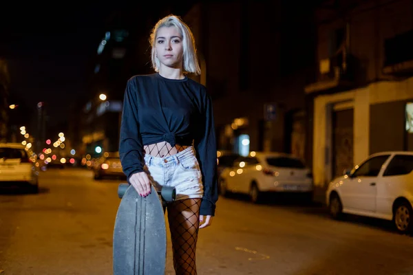 여자가 스케이트보드를 거리에 반바지를 바라보고 있습니다 — 스톡 사진