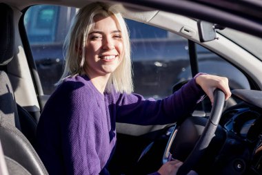 Genç kadın sürücü arabada oturuyor, sürüyor.