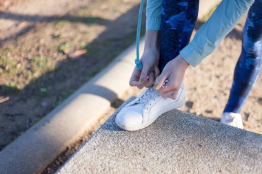 Parkta ayakkabı bağcıklarını bağlayan kadın.