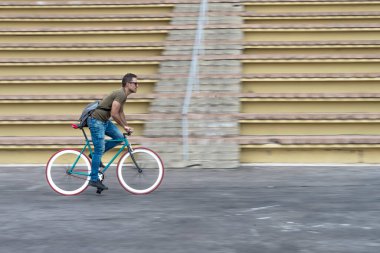 Delikanlı şehir caddesinde sabit vites bisikleti sürüyor.