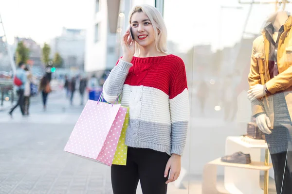 携帯電話を使用しながらショッピングセンターに立つ若い女性の正面図 — ストック写真