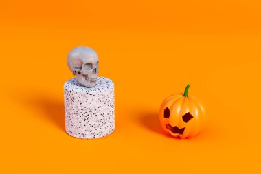 Cadılar Bayramı balkabağı ve beyaz kafatası turuncu arka planda yüz yüze. 3d hazırlayıcı
