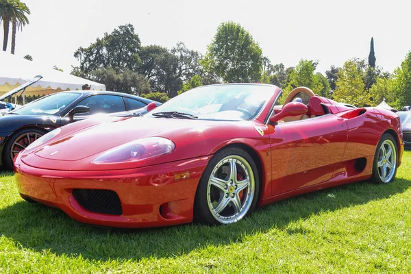 Red Ferrari GT displayed on the grass at a car show