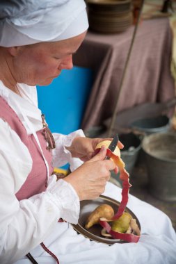 HIERDEN, NETHERLANDS - 10 HAZİRAN 2019: Ortaçağ giysileri içinde bir elma soyan kadın