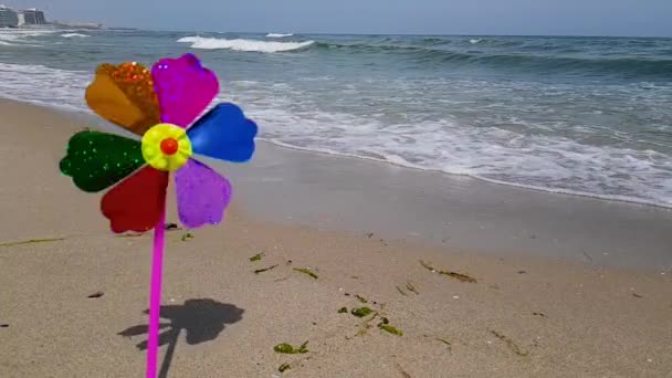 Moulin à vent pour enfants sur la mer. Un moulin à vent pour enfants dans le vent, un moulin à vent pour enfants coloré tourne du vent sur le bord de la mer. — Video