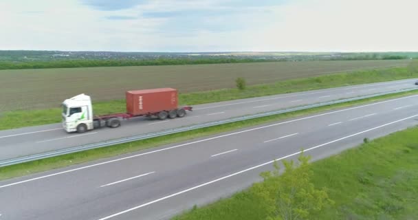 Грузовик едет по современному шоссе вокруг зеленой травы. Грузовик на шоссе с беспилотника. — стоковое видео