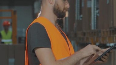 Büyük bir fabrikanın depo müdürü. Bir depoda elinde tablet olan bir müdür malları kontrol ediyor..