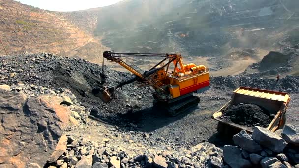 An excavator pours soil into a dump truck in a quarry. Iron ore mining in an open pit. Equipment for the extraction of iron ore in a quarry — Stock Video