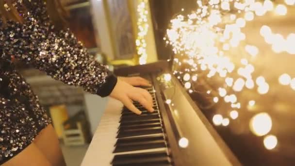 Жінка грає синтезатор в інтер'єрі Нового року. Руки грають синтезатор. Відтворення синтезатора — стокове відео