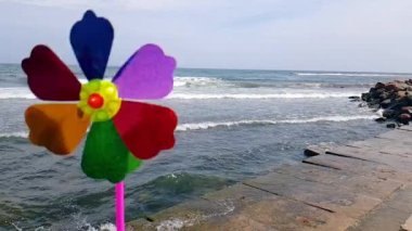 Denizde çocuklar yel değirmeni. Rüzgardaki bir çocuk yel değirmeni, deniz kıyısındaki rüzgardan dönen renkli bir çocuk değirmeni..