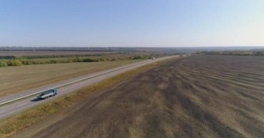 Bir kamyon tarlaların üst manzarası arasında güzel bir yol boyunca gidiyor. Bir kargo kamyonu otoyol boyunca gidiyor. Bir İHA görüntüsü.