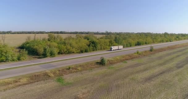 Ciężarówka jedzie wzdłuż pól w słoneczną pogodę. Ciężarówka jedzie piękną drogą. Ciężarówka jedzie wzdłuż pola widok z góry. — Wideo stockowe