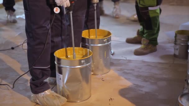 Farbe in einem Eimer verrühren. Eine Nahaufnahme von gelber Farbe, die in einem Eimer gerührt wird — Stockvideo