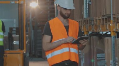 Fabrika deposunda tabletli bir adam. Depoda çalışan bir işçi bir tur atar..