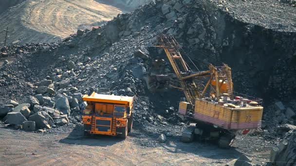 Una excavadora en una cantera carga tierra en un camión volquete. El proceso de extracción de mineral de hierro en una cantera. Equipo para la extracción de mineral de hierro en un pozo abierto. El proceso inteligente en una cantera de mineral de hierro — Vídeo de stock