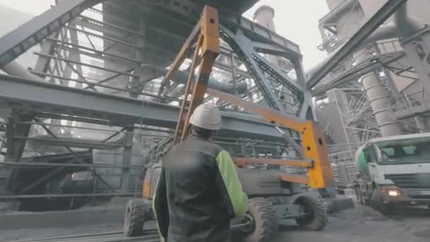 Metalurji fabrikasında bir adam. Bir işçi büyük bir fabrikadan geçer. Metalurjik bir fabrikada devasa metal yapılar. — Stok video