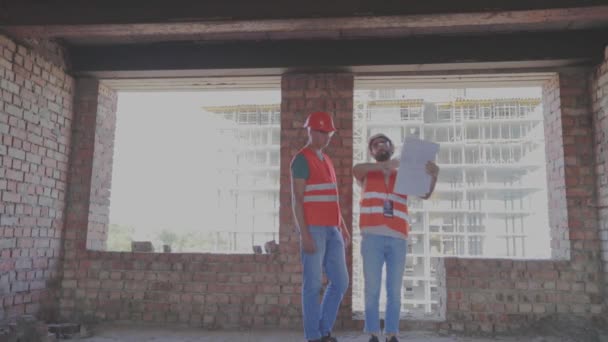 Byggare inne i en ny byggnad. Ingenjörer med ritning inne i ett nytt hus — Stockvideo