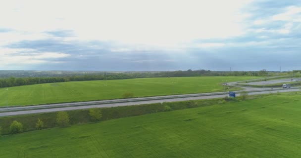 Vrachtwagen rijdt op de moderne snelweg rond groen gras bovenaanzicht. Vrachtwagen op de snelweg uitzicht vanaf de drone. — Stockvideo