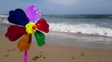 Renkli bir çocuk yel değirmeni deniz kıyısında rüzgardan dönüyor. Denizde çocuklar yel değirmeni. Rüzgarda savrulan bir çocuk değirmeni