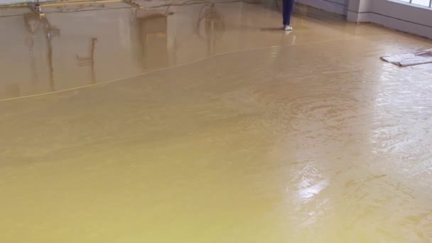 Pouring self-leveling floors. Self-leveling floors on a large area, a worker pours self-leveling floor in a factory workshop — Stock Video