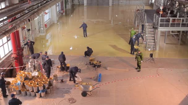 Piso auto-nivelante na oficina. Os construtores fazem um piso auto-nivelante na oficina da fábrica. Piso auto-nivelamento sobre uma grande área. — Vídeo de Stock