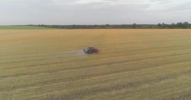 Rozpylanie pola z widokiem na pszenicę z drona. Ciągnik spryskuje pszenicę herbicydami. Ciągnik rozpyla pola pszenicy. — Wideo stockowe