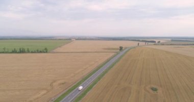 Yol anteninin yanındaki buğday tarlasında. Renkli bir buğday tarlasının yanında arabaları olan bir otoyol. Yolun yanındaki buğday tarlasında uçarken