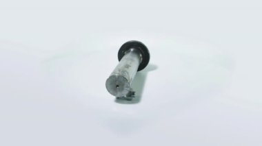 Metal cıvata beyaz arka planda döner. Arka planda beyaz bir kilit var. Beyaz arkaplanda sürgü