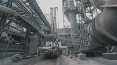 Metalurji fabrikasında bir adam. Bir işçi büyük bir fabrikadan geçer. Metalurjik bir fabrikada devasa metal yapılar.