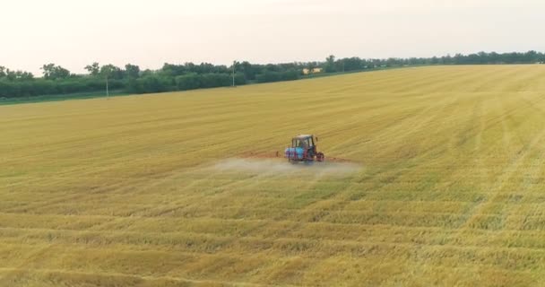 O trator pulveriza os campos de trigo. Pulverizando um campo com vista de trigo de um drone. Um trator pulveriza trigo com herbicidas. — Vídeo de Stock