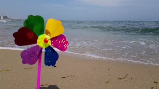 Wiatrak dla dzieci na morzu. Wiatrak dla dzieci. Kolorowy wiatrak dla dzieci wiruje nad brzegiem morza.. — Wideo stockowe