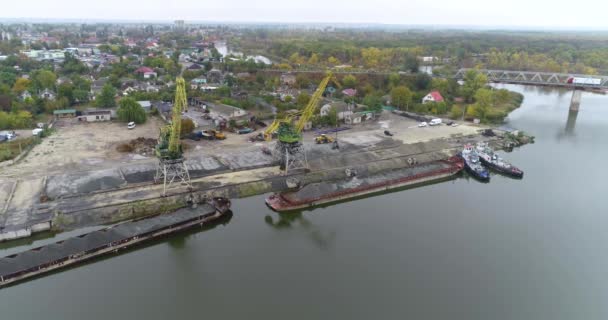 Duże dźwigi w porcie rozładowują barkę z materiałem, dźwigi portowe pracują od góry — Wideo stockowe